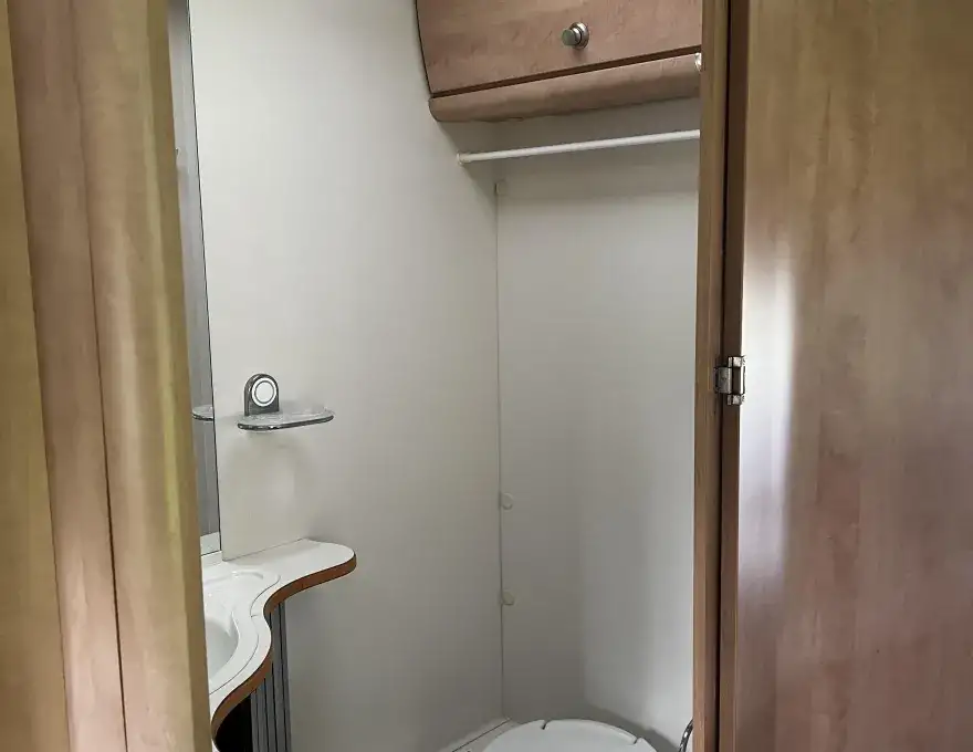 Toiletruimte met draaibaar toilet, kastruimte en wastafel met kastruimte 
